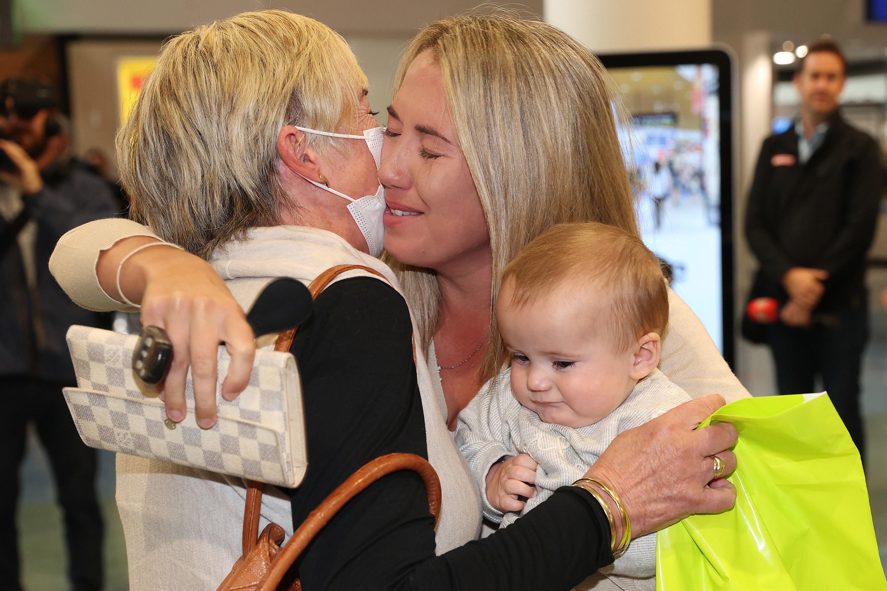 A baby gets sandwiched between two people embracing