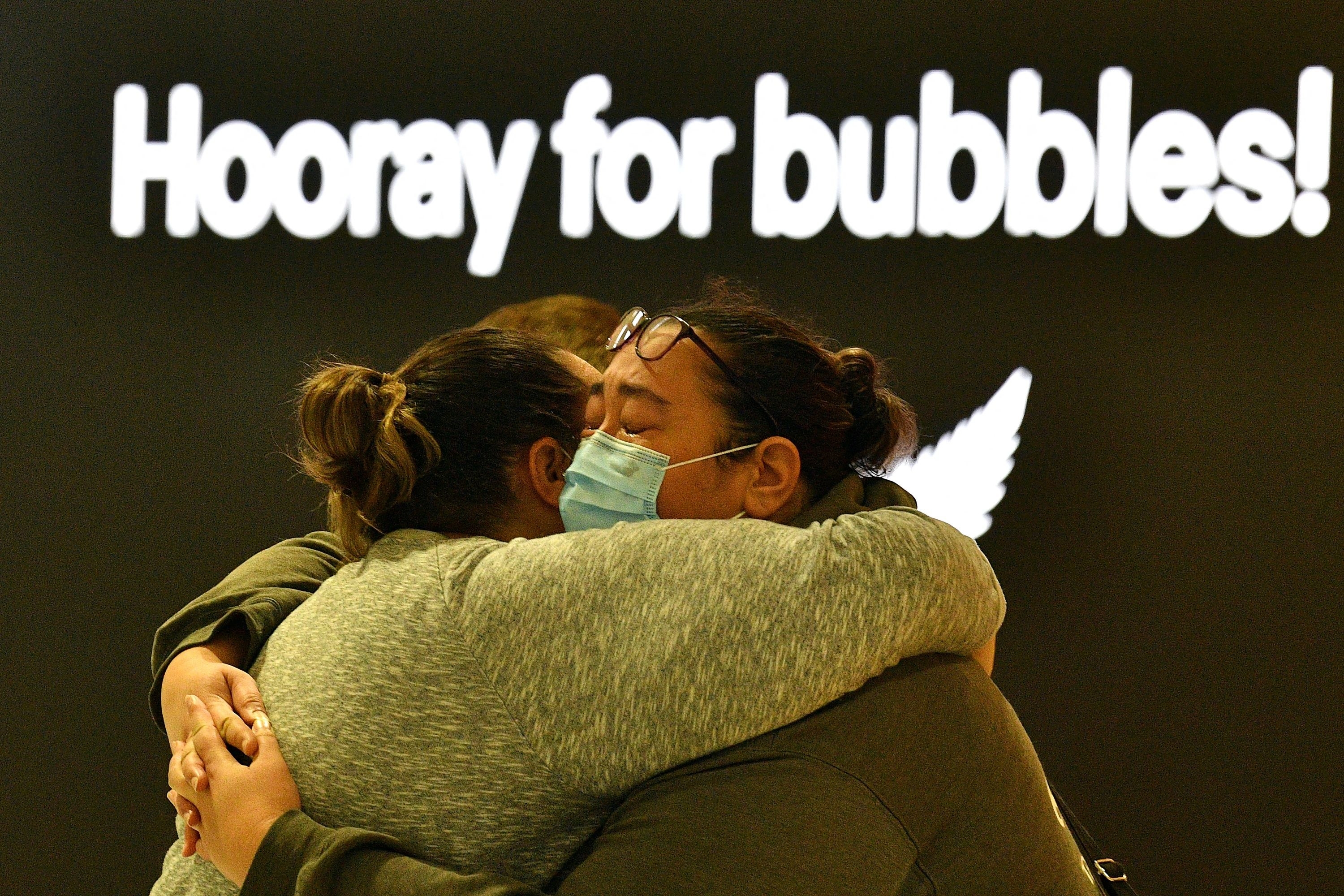 Two people embrace with a sign that says &quot;hooray for bubbles!&quot; above them