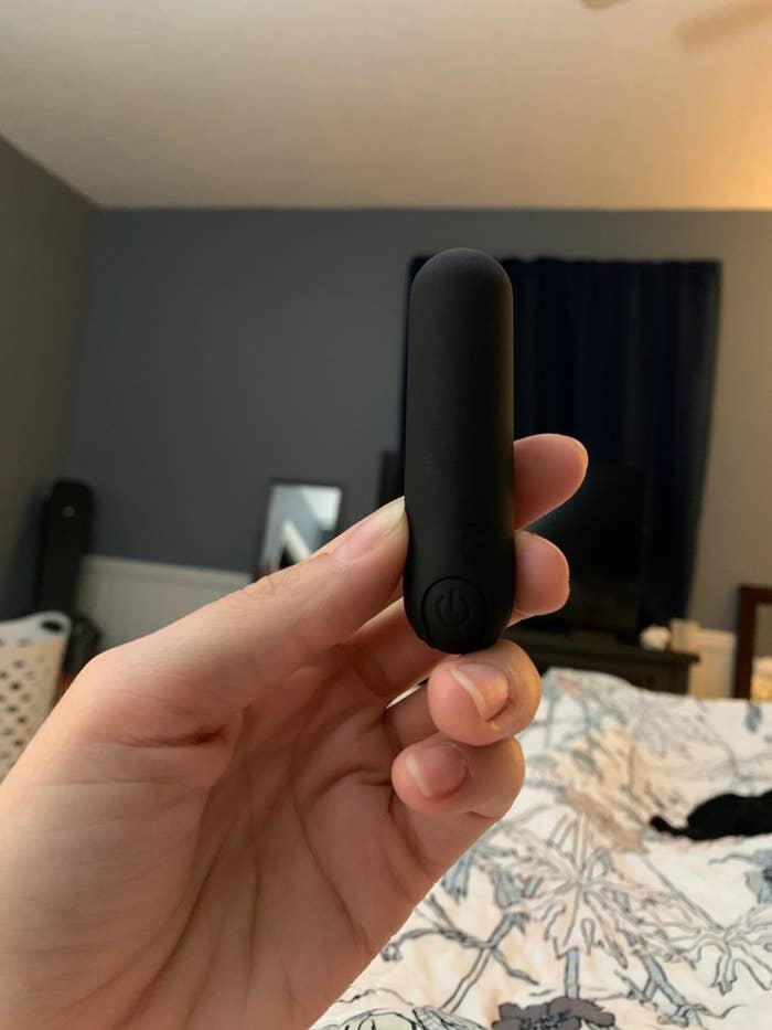 reviewer hand holding up the black bullet vibrator between fingers