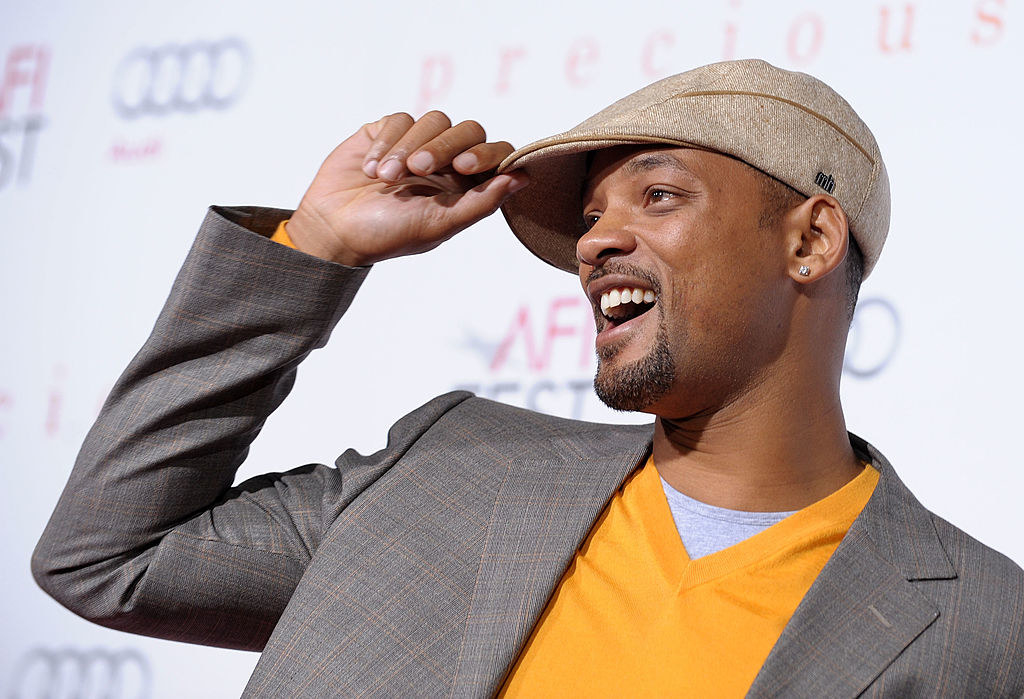 Side view of smiling Will on the red carpet wearing a cap