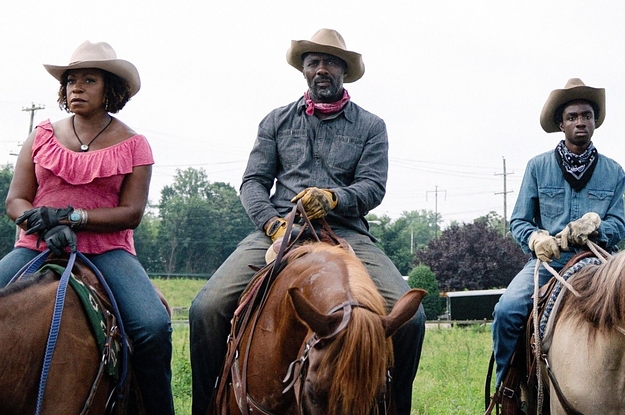 Cowboys and cowgirls sit on their horses side-by-side