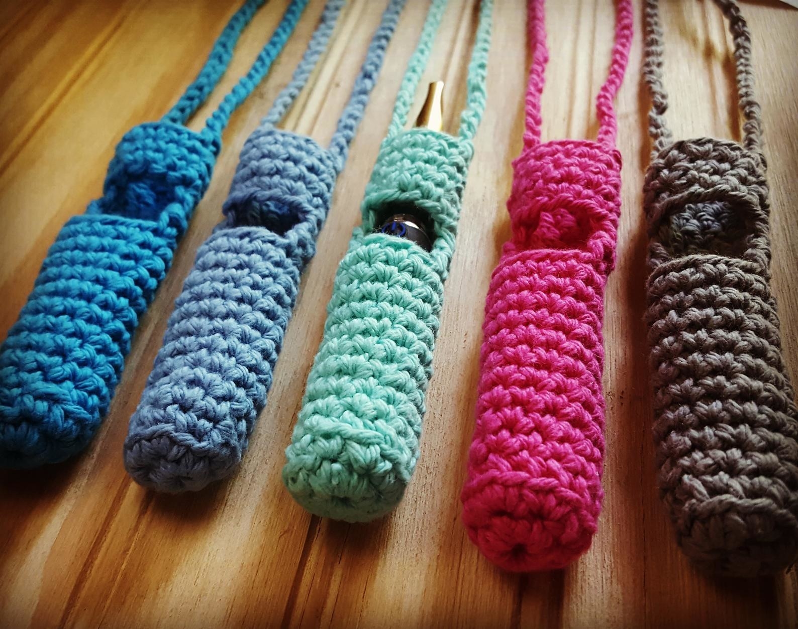 five knitted vape holders in different colors including two blues, mint green, pink, and gray. They all have a knitted lanyard too.