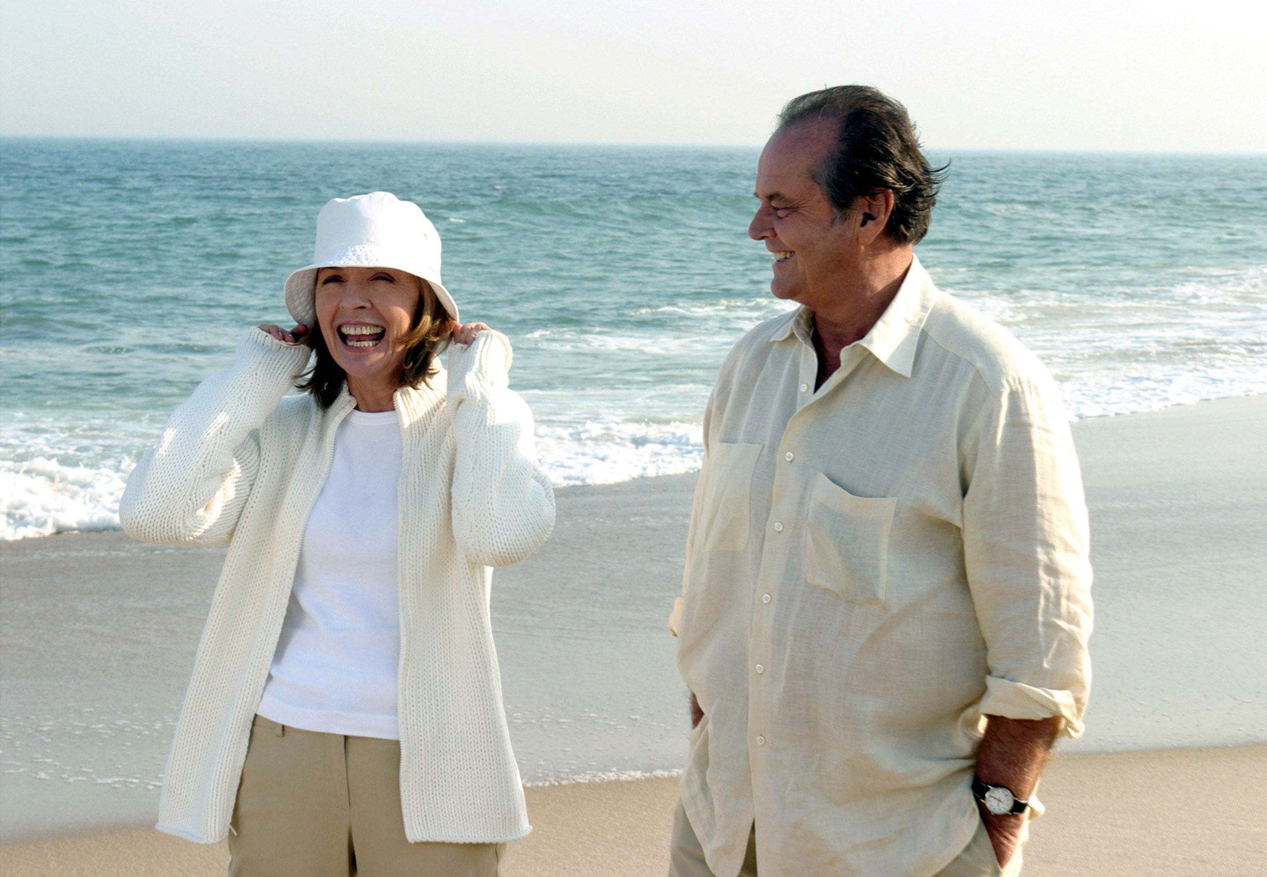 an older couple walking happily down the beach