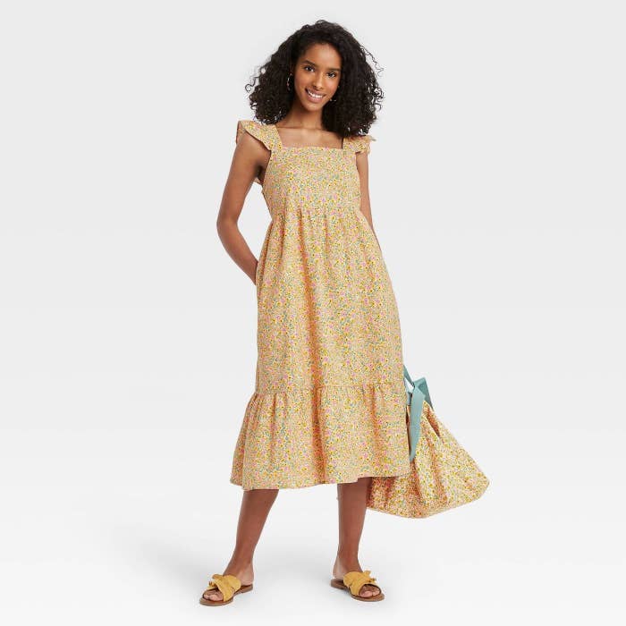 Model wearing yellow floral dress with hemmed skirt 