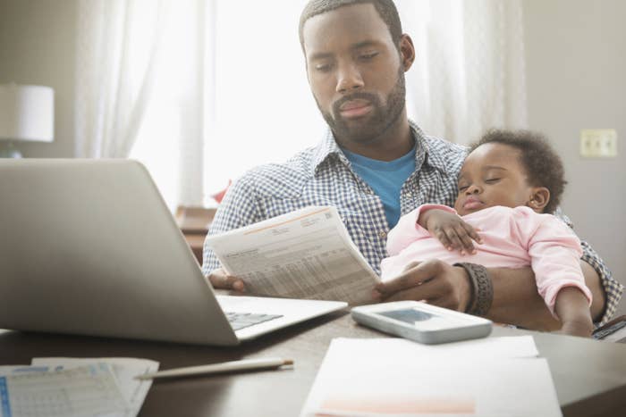 a dad reading bills holding his baby daughter