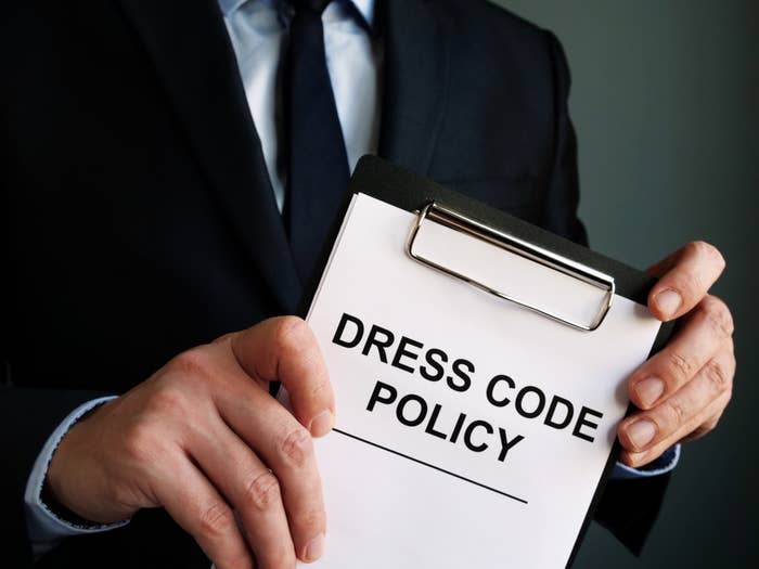 Hands holding a clipboard that says "dress code policy"