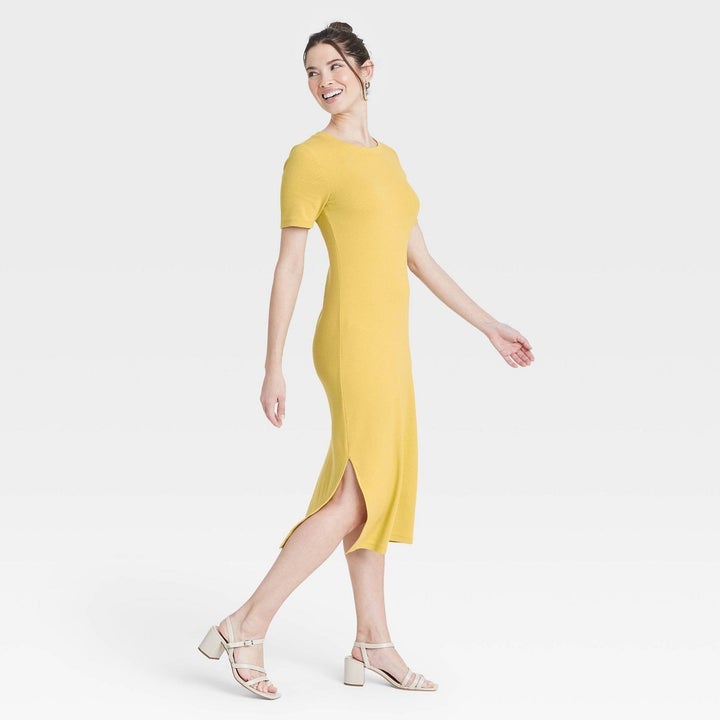 Model wearing yellow dress with two slits on both sides, goes past the knee