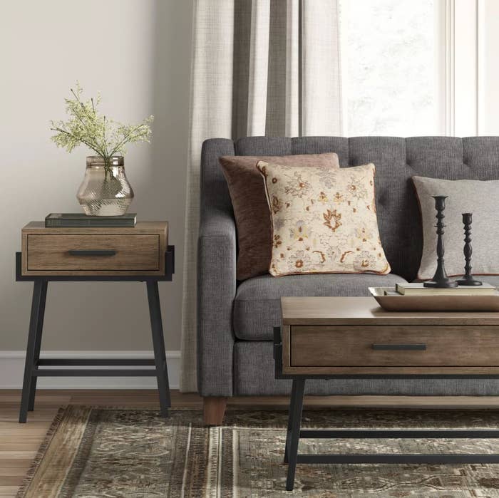 The angled side table in wood next to a gray couch