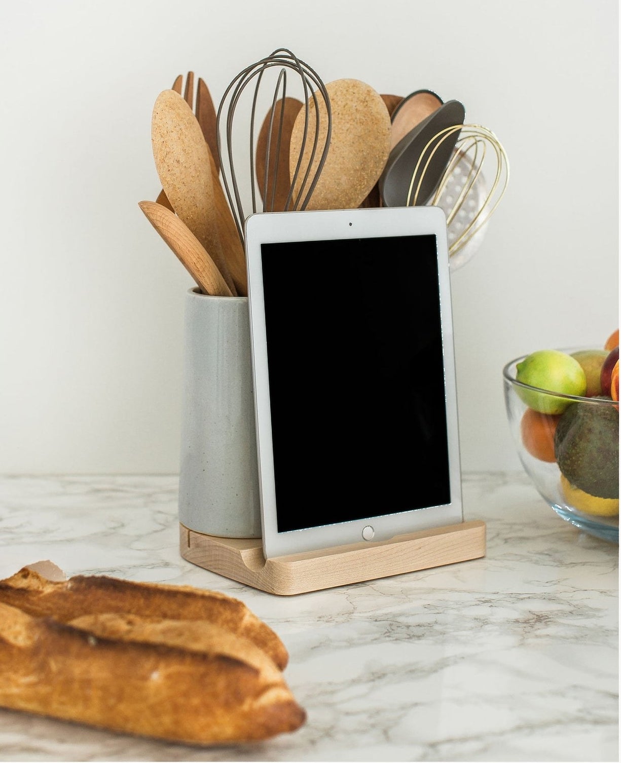 wood base tablet dock and grey ceramic holder with kitchen utensils in it