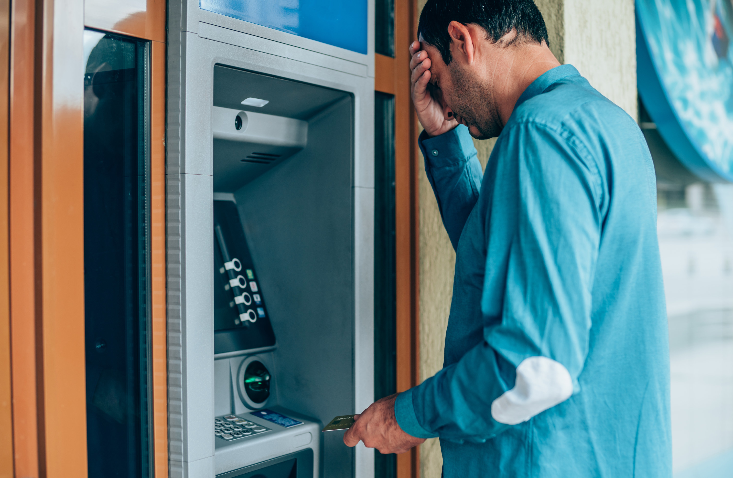 Person holding their forehead in stress at an ATM