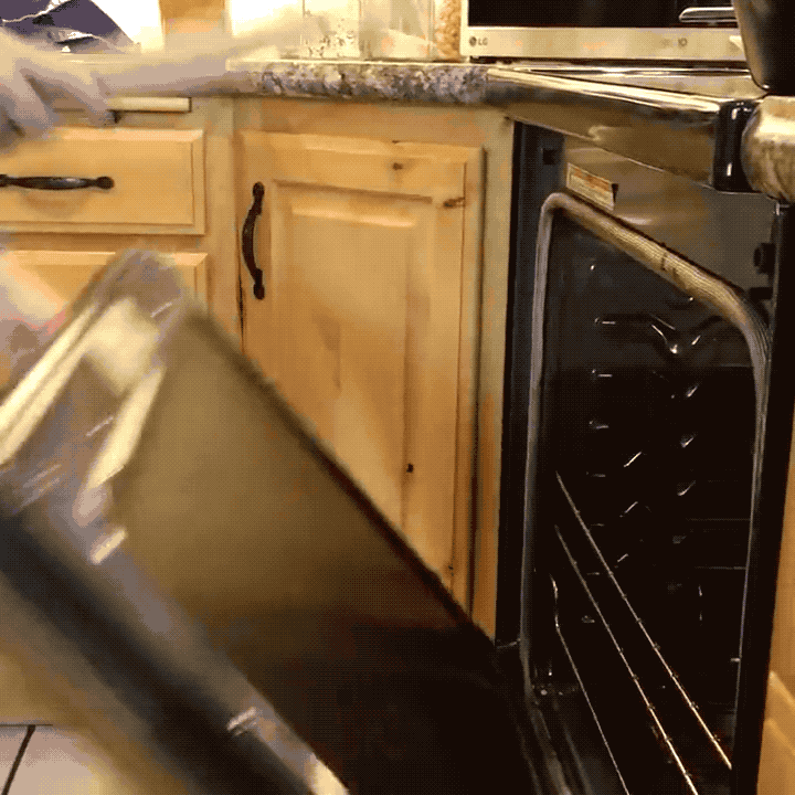A gif of a model using the chicken-shaped stick to pull out and push in an oven rack with a dutch oven on it