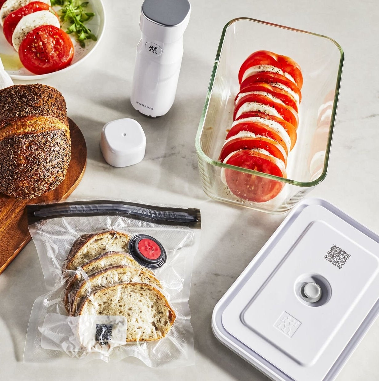 A bag with bread vacuum sealed, a container with tomato and mozzarella, and the small vacuum pump