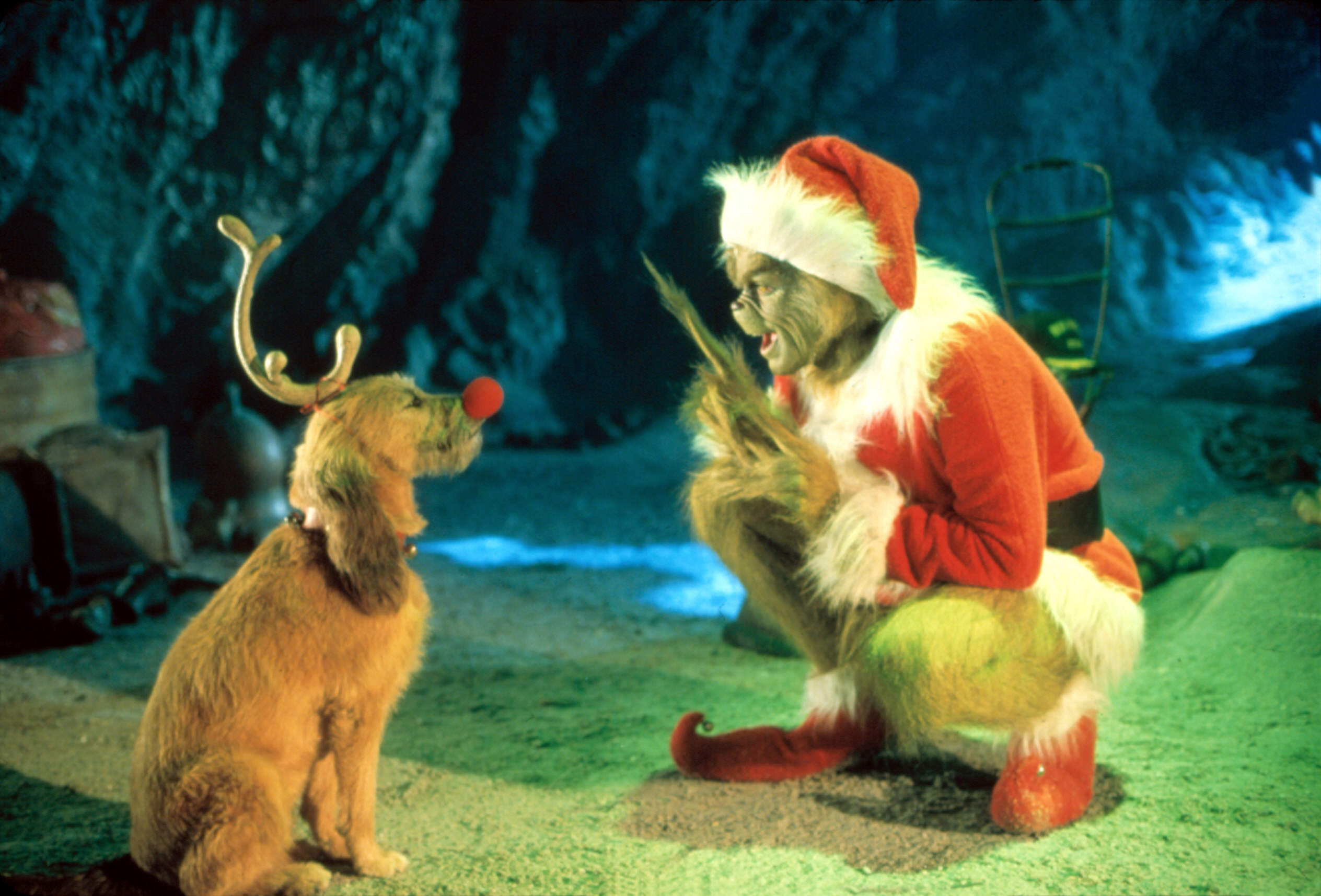 Photo of the Grinch dressed as Santa talking to his dog