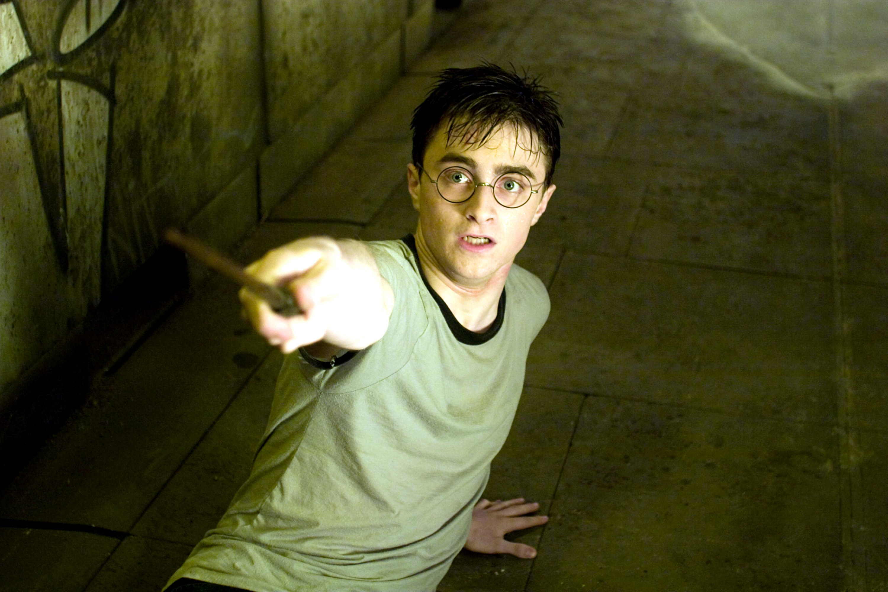 Photo of Harry Potter on the ground looking scared and pointing his wand