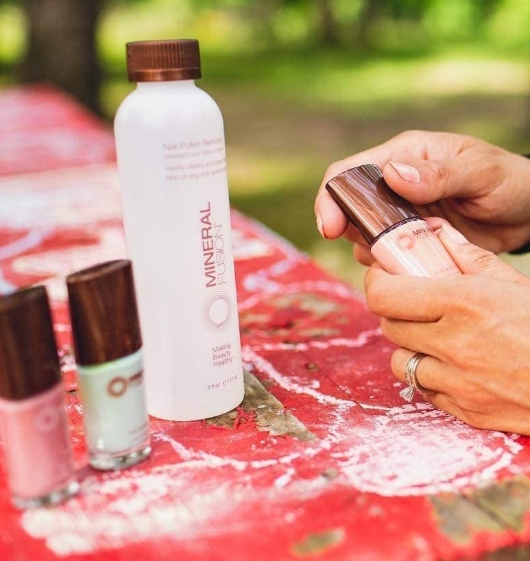 A person holding a bottle of nail polish next to the remover