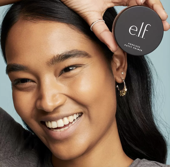model holding primer next to face and smiling