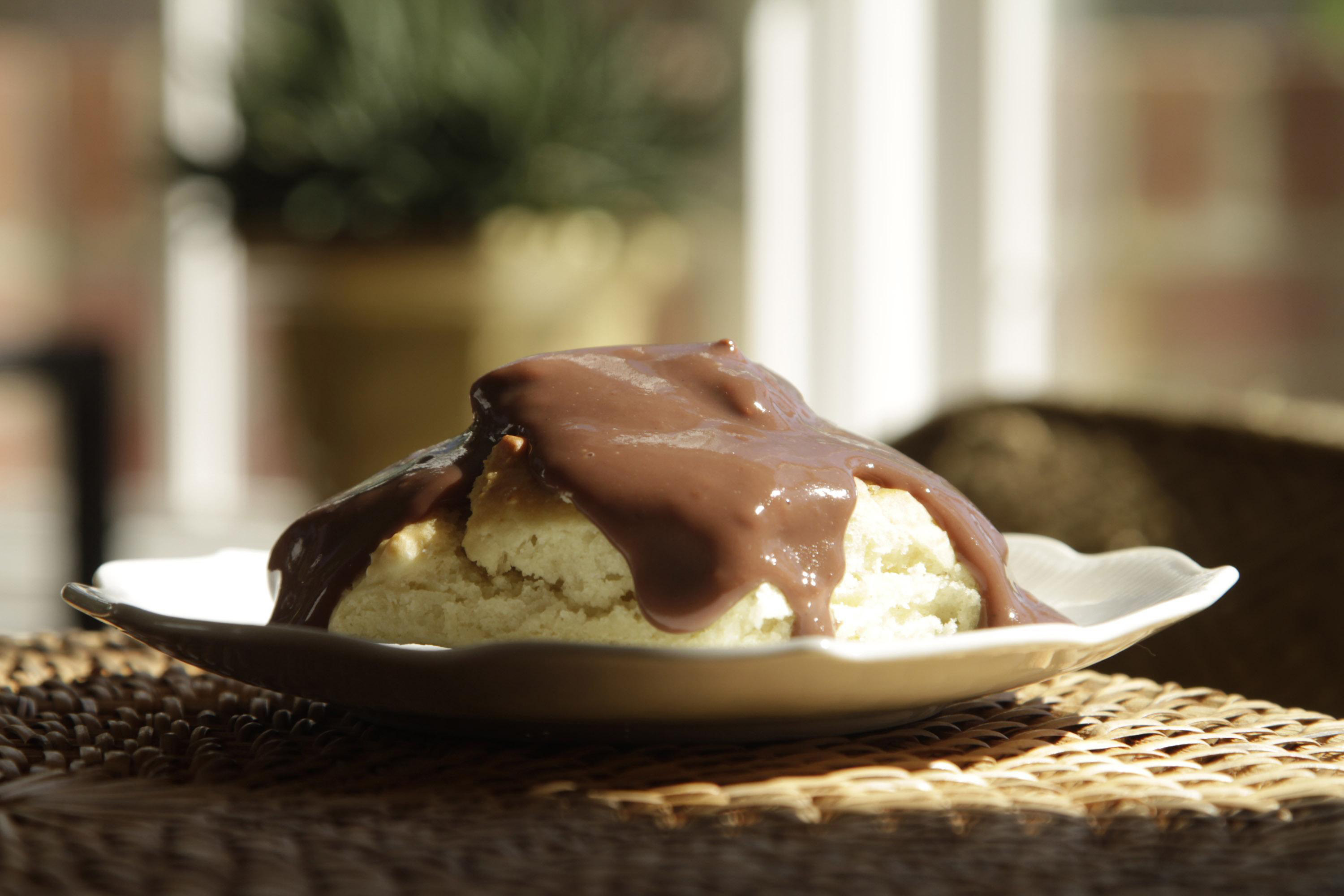 Soft-lit ceramic plate containing warm biscuits and gooey chocolate gravy on top