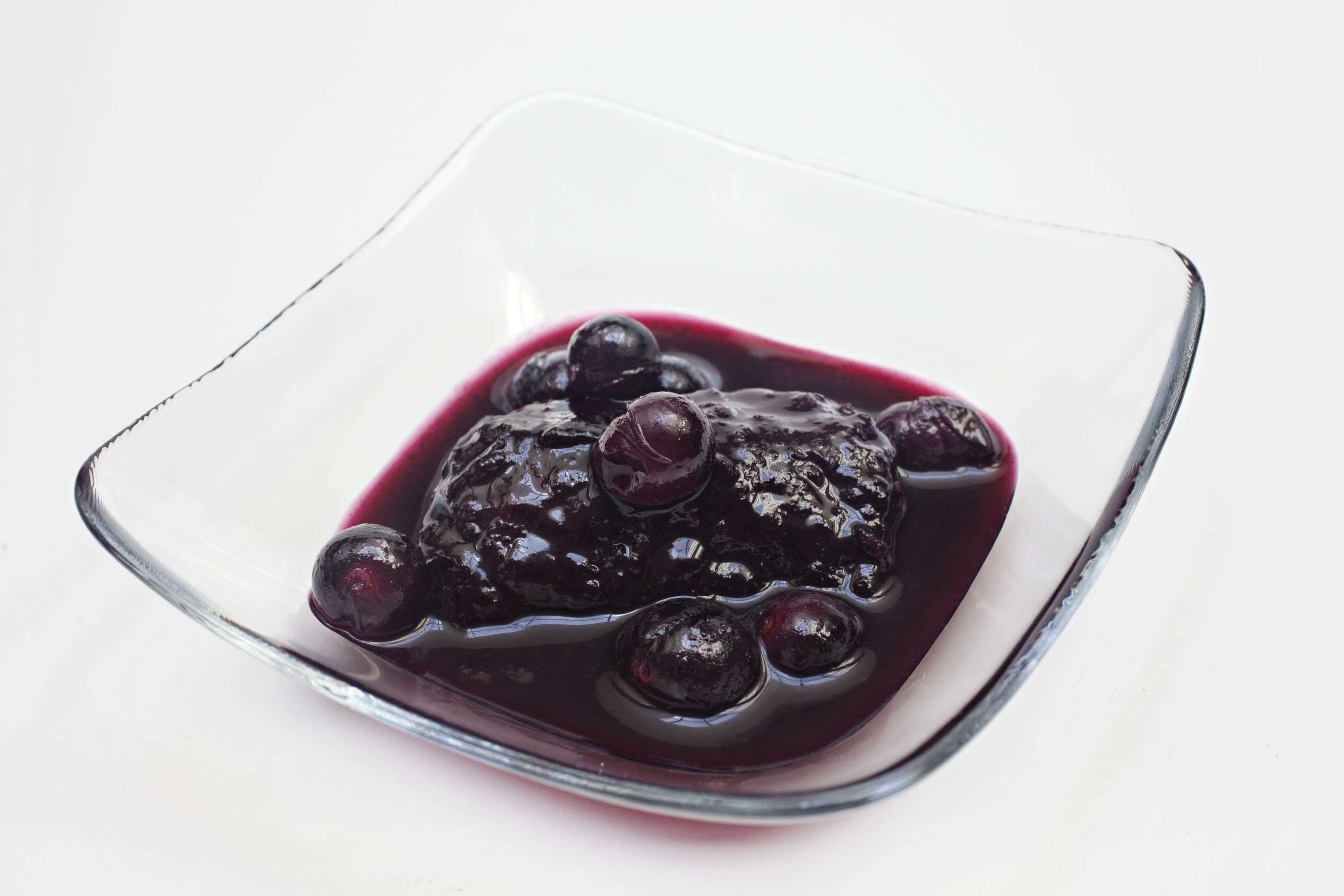 Glass bowl filled with grape syrup, grapes, and grape dumplings