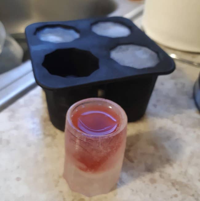 reviewer's ice shot glass next to black silicone mold