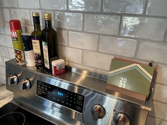 Reviewer&#x27;s picture of their olive oil bottles and more stored on the stove&#x27;s magnetic strip 