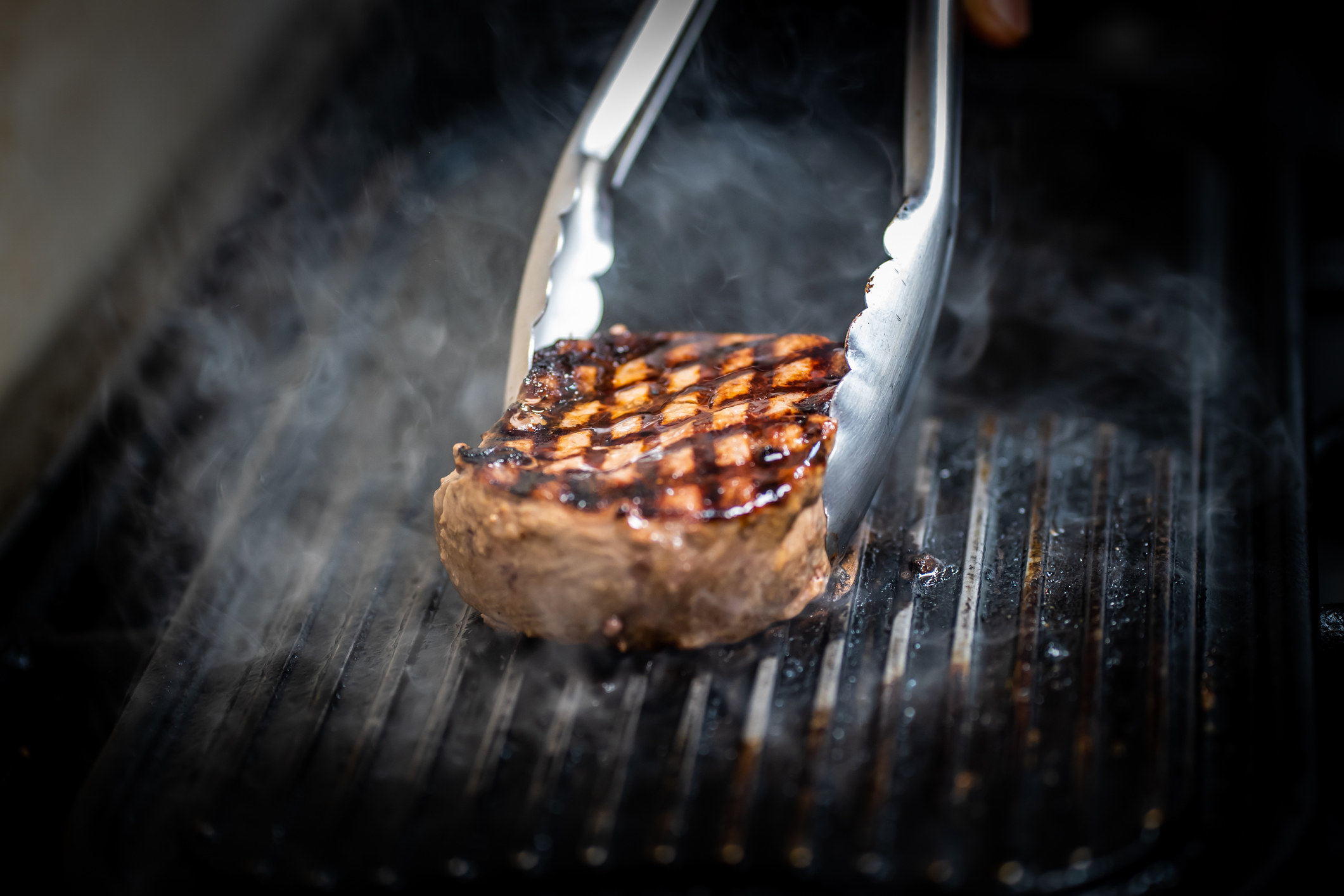 a steak being cooked with tongs