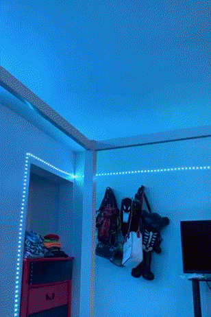 a gif of a room with light strips installed that are changing colors 