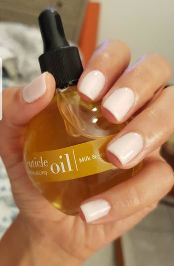 a reviewer holding the milk- and honey-infused cuticle oil