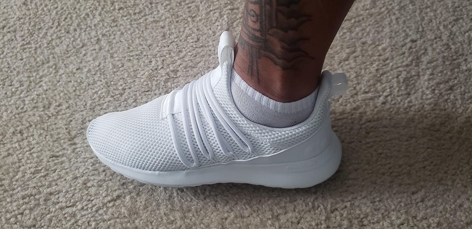 A reviewer wearing the laced white shoe made of mesh fabric with a loop on the heel