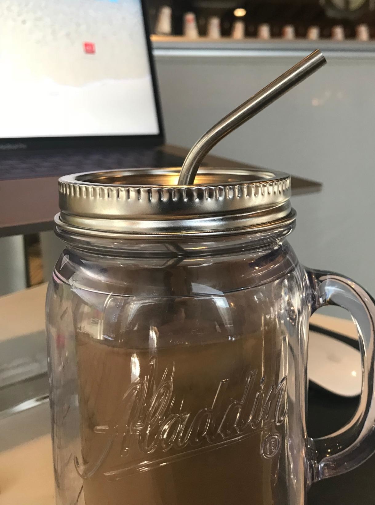 reviewer image of a stainless steel straw in a mason jug of iced coffee