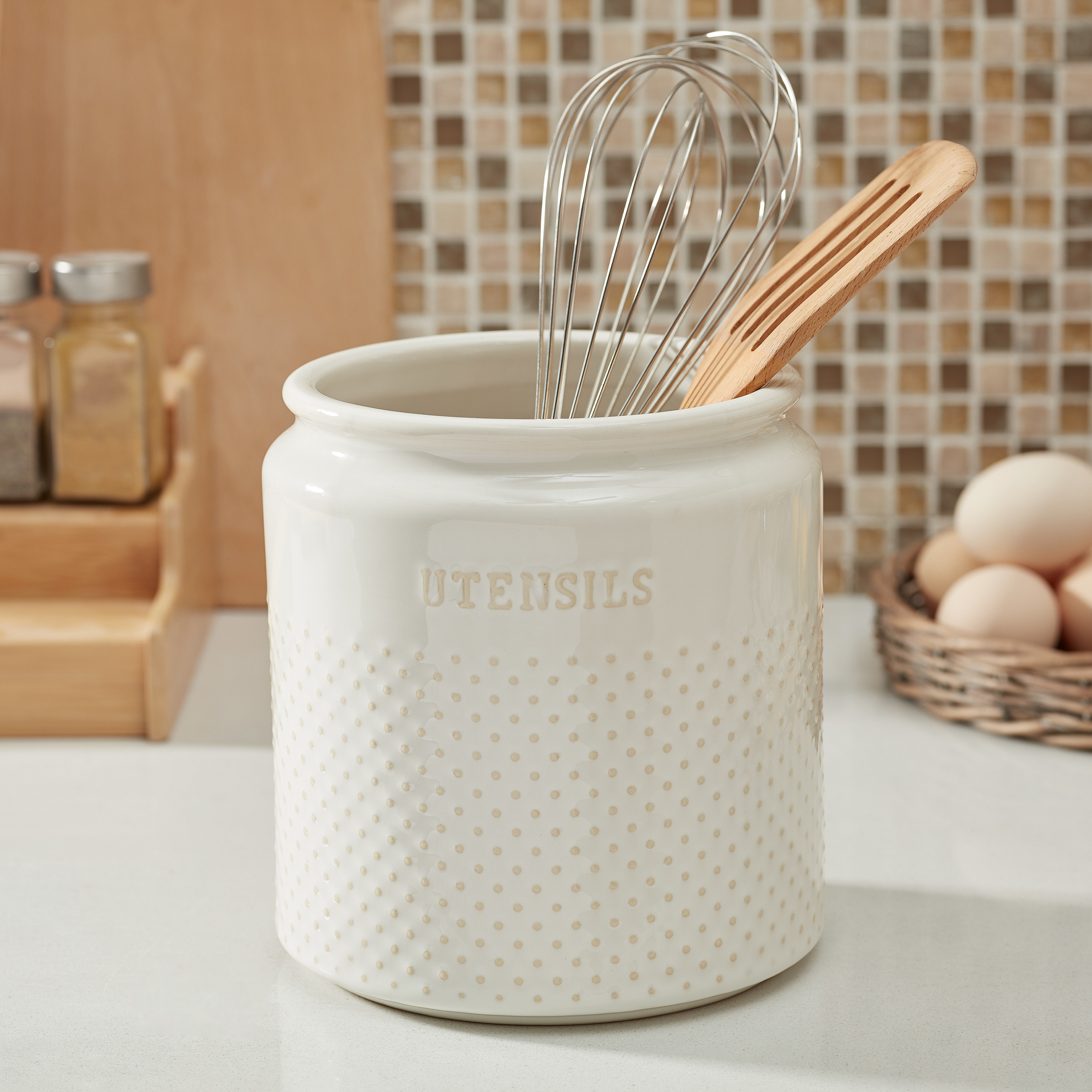 white dotted ceramic utensil holder with &quot;utensils&quot; printed on the front, on a counter