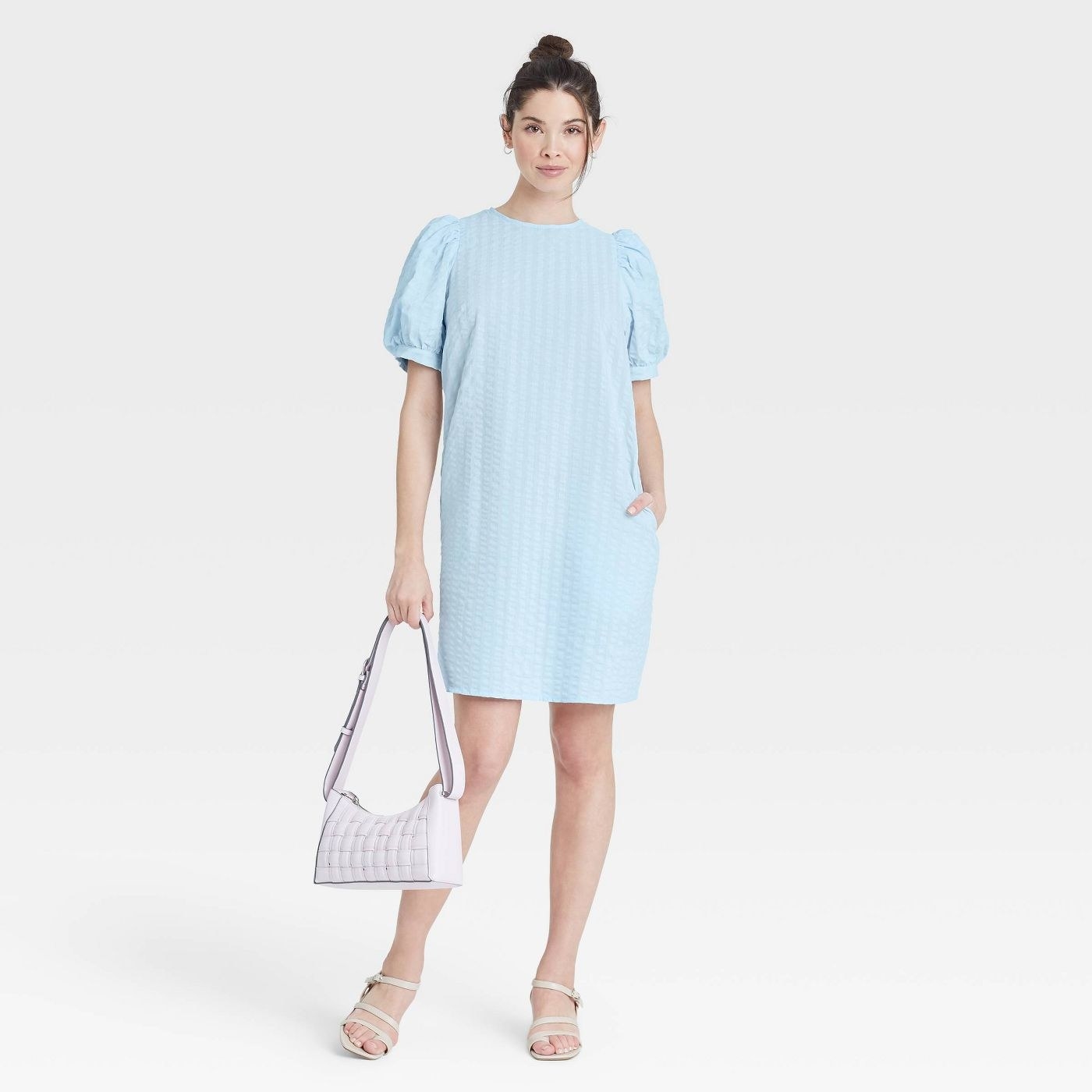 Model wearing blue dress with puff sleeves, goes past the thighs