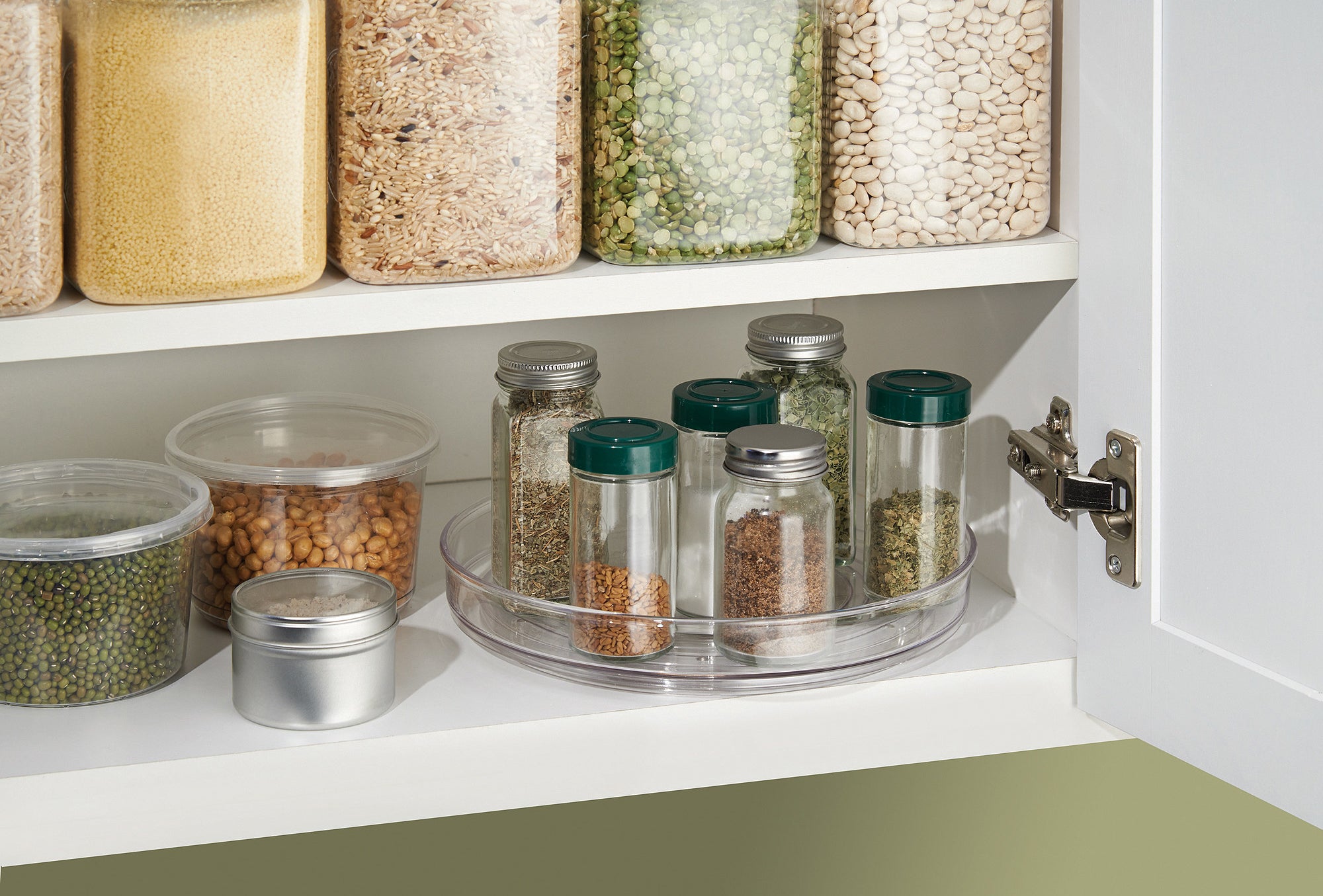 clear turnable holding spice jars on the bottom shelf of a cabinet