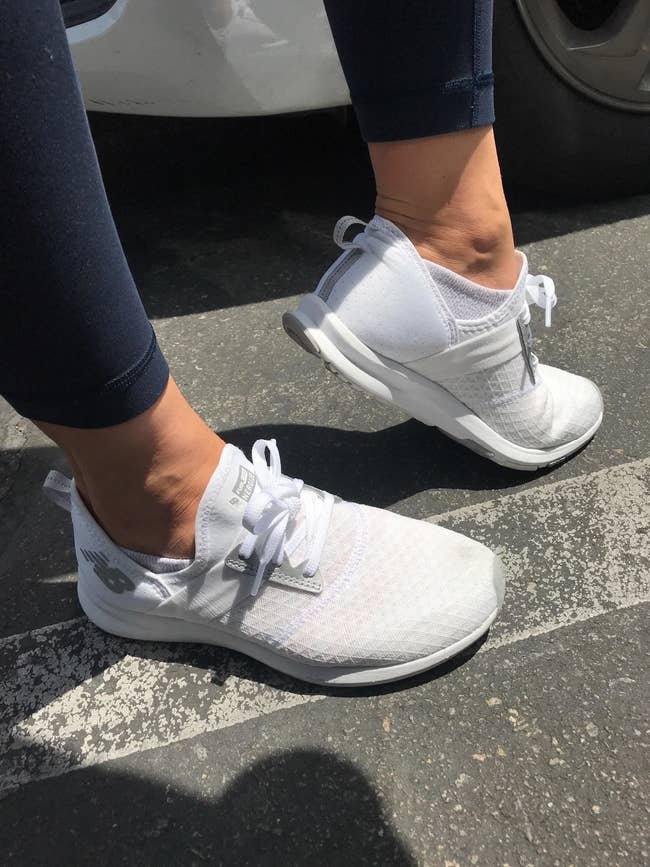 A reviewer wearing the shoes in white with a mesh, breathable exterior