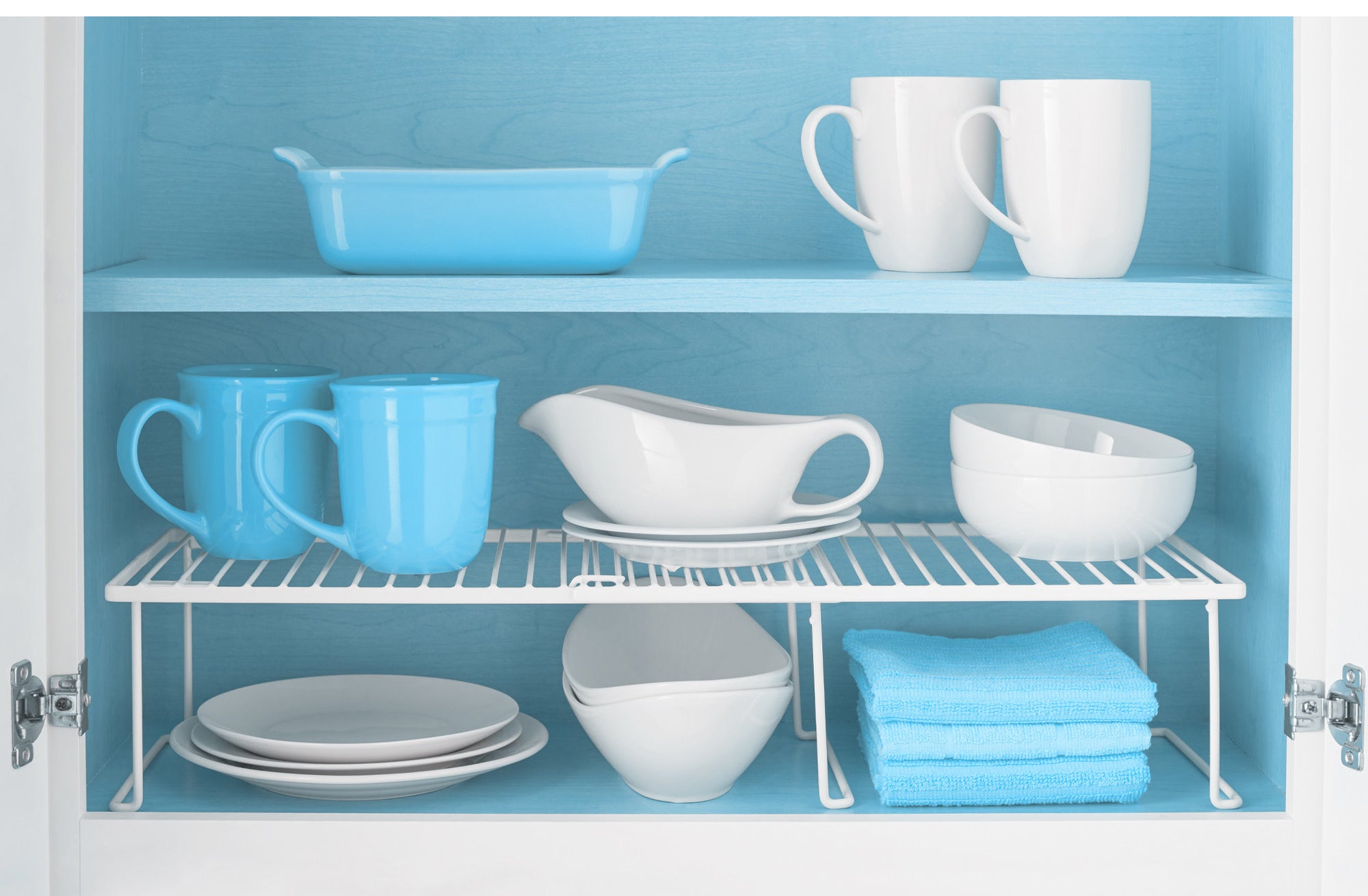 white expandable cabinet shelf with cups and bowls on top and plates underneath