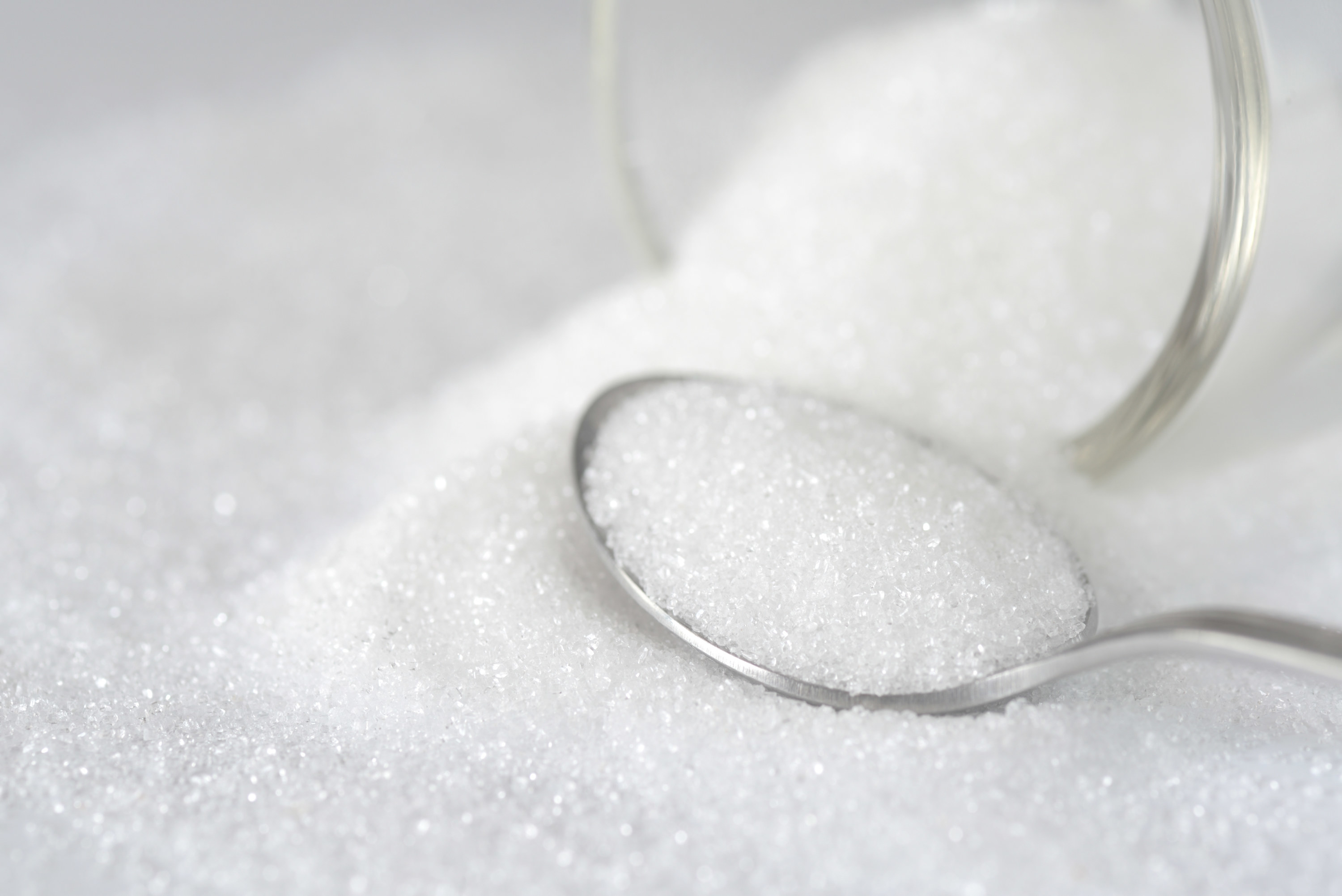 Spilled white sugar in a spoon