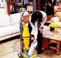 Monica cleaning a big vacuum with a smaller vacuum.