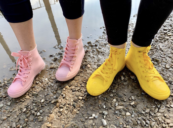 two reviewers wearing high-top sneaker style rain shoes in light blue and yellow