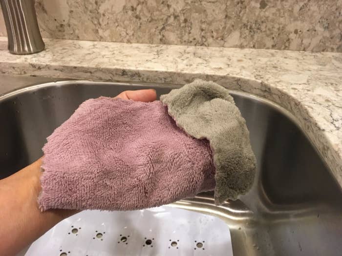 close up of the pink and grey coral dishcloth in their hand at their kitchen sink