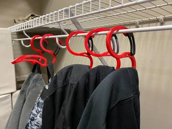 Five hoodie hangers hanging in a closet with hoodies on them