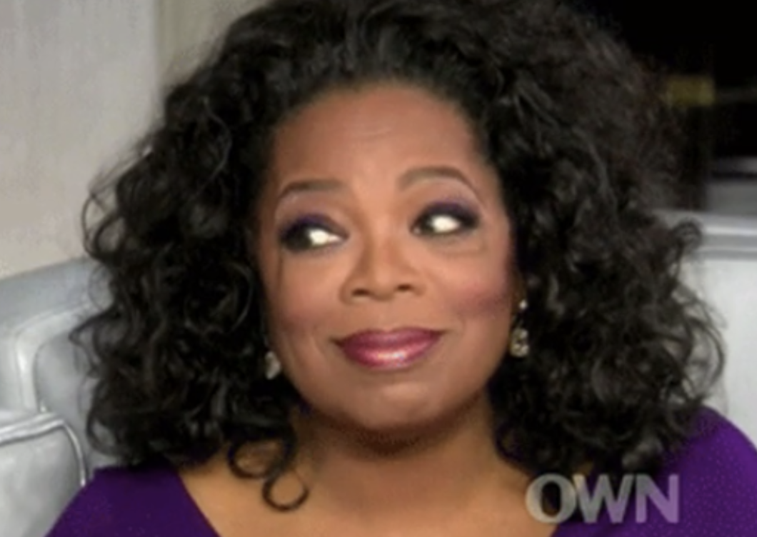 Oprah with her eyes widened and a slight smile