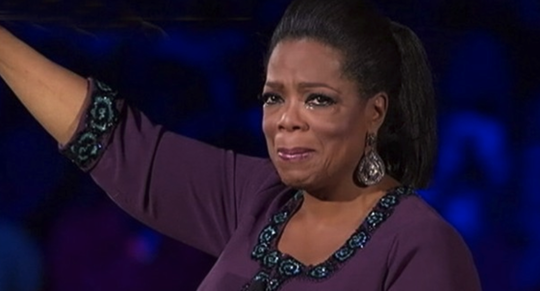 Oprah crying and holding her hand up