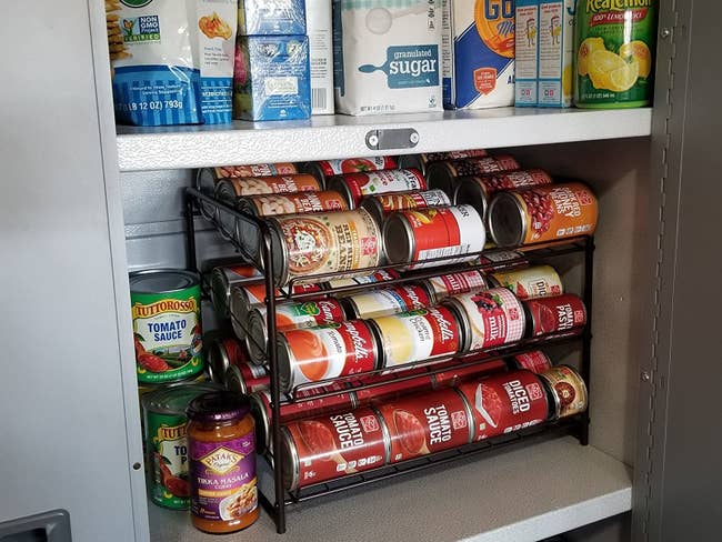 reviewer photo showing the can organizer in their pantry filled with cans 