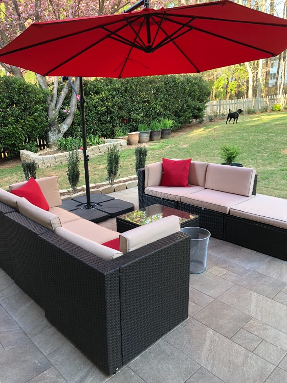 red umbrella on reviewer&#x27;s patio, casting shade over two halves of an outdoor sectional sofa