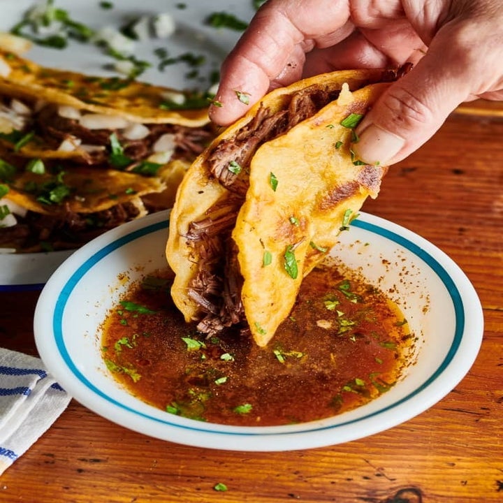 Dipping a birria taco into broth.