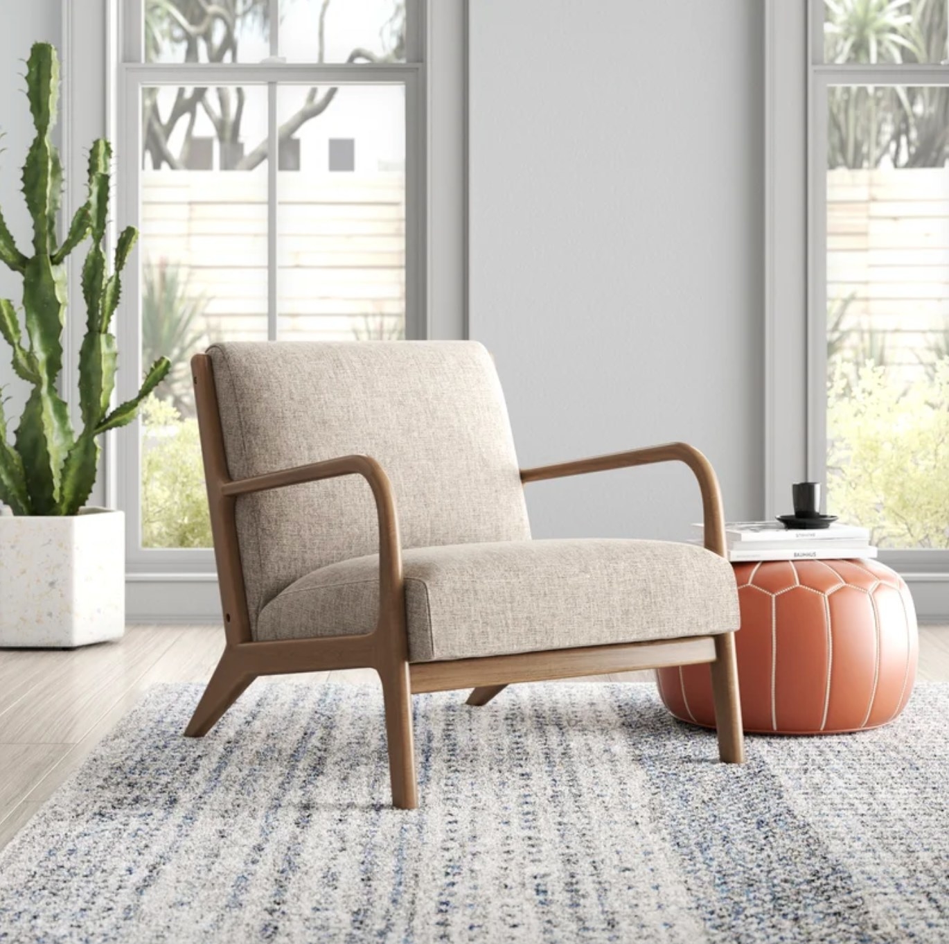 The midcentury armchair in taupe next to an orange pouf