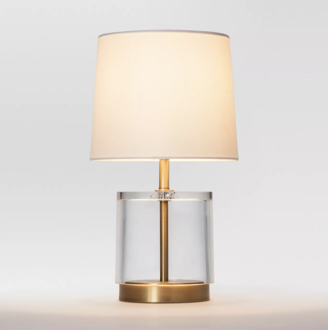 the acrylic and brass table lamp with a beige lampshade 