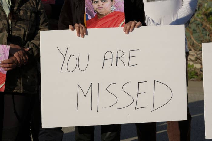Someone holds up a sign that reads "you are missed"