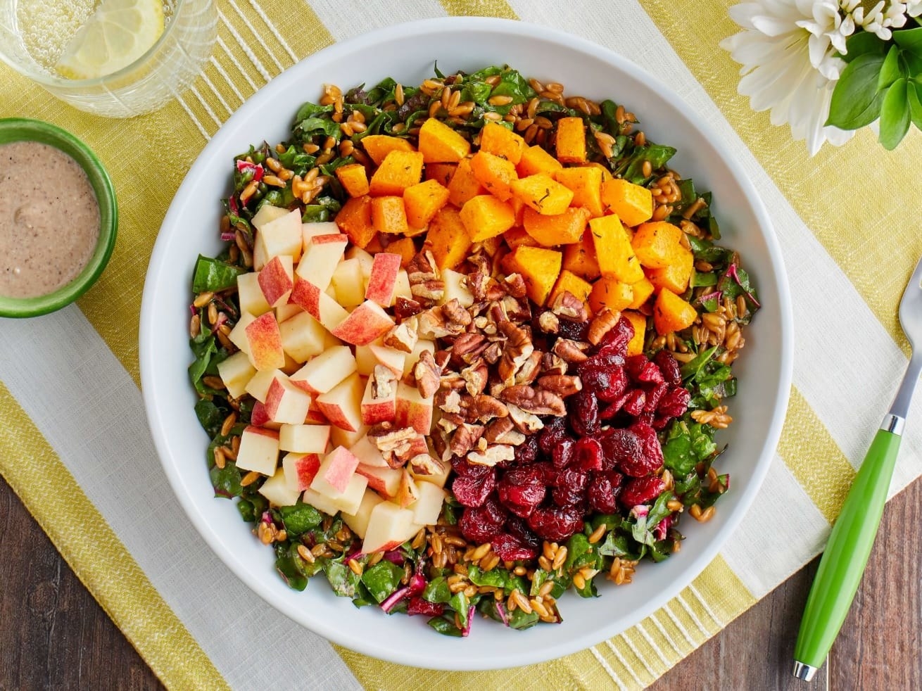 a harvest salad with apples, cranberries, walnuts, and squash over greens