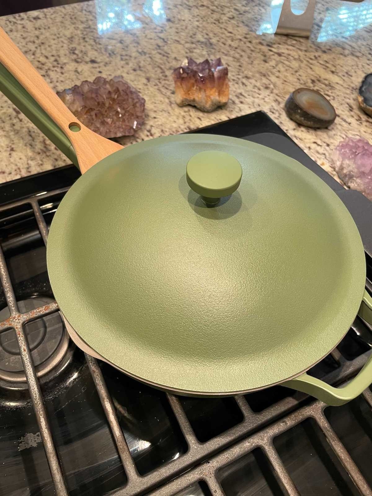 green pan with spatula held onto the handle with a node 
