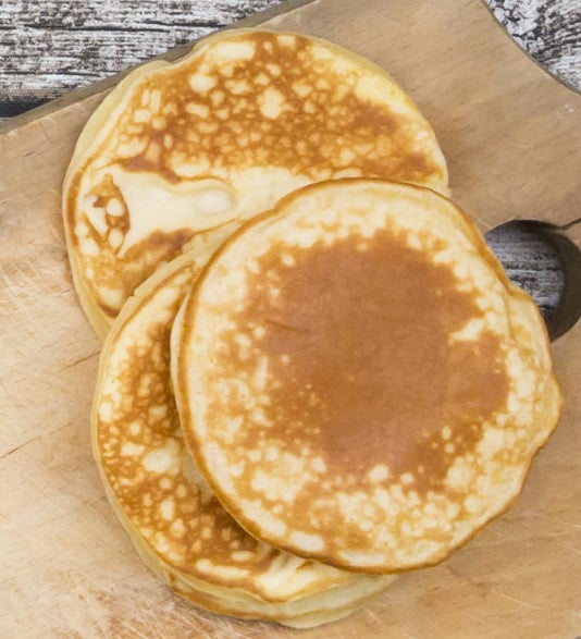 A stack of pikelets on a wooden chopping board